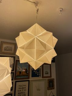 an origami chandelier hanging from the ceiling in a room with pictures on the wall