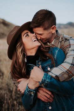 a man and woman hugging in the middle of a field