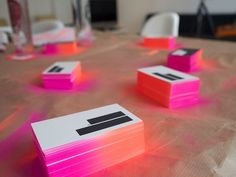 some pink and orange cards sitting on top of a table with chairs in the background