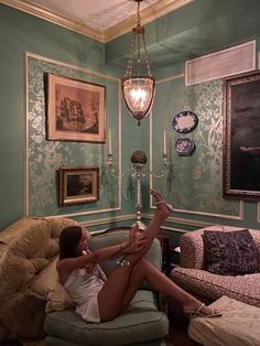 a woman is sitting on a chair in a room with green walls and blue wallpaper