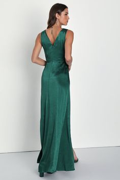 a woman in a long green dress looking back at the camera with her hand on her hip