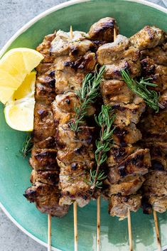 grilled meat on skewers with lemon wedges and rosemary garnish