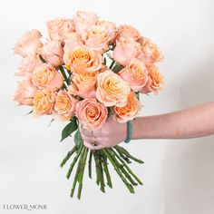 a person holding a bouquet of peach colored roses