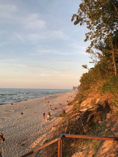 people are walking on the beach at sunset