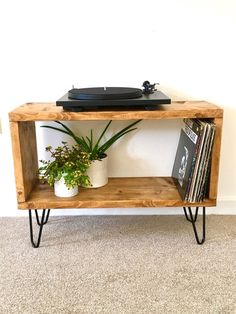 an old record player is on top of a wooden shelf next to a potted plant