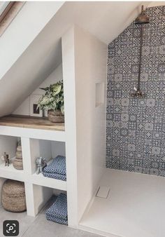 a bathroom with blue and white tiles on the shower wall, shelves in the corner