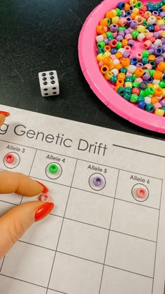 a child's hand is pointing at a game board with beads on it and two dices next to it