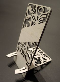 an intricately designed wooden card holder on a black surface with silver accents and metal handles