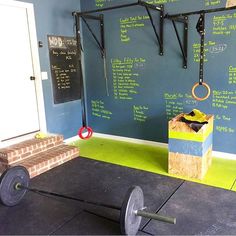 an exercise room with chalkboard walls and barbells on the wall next to a bench