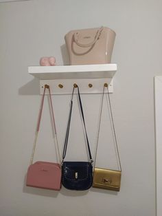 three purses are hanging on the wall next to a shelf with other purses