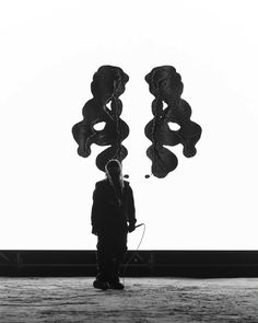 a man standing in front of a kite flying through the air with two strings attached to it