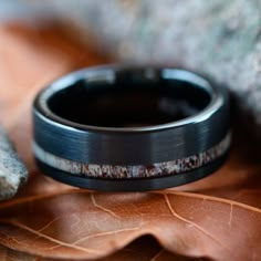 a wedding band with an antler wood inlay sits on top of a leaf