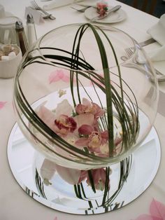 a glass vase with flowers in it sitting on top of a white tablecloth covered table