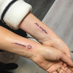 two people holding hands with tattoos on their arms that say i love you and someone else