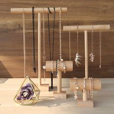 several necklaces are hanging from wooden poles on the table next to other jewelry items