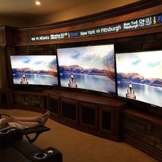 a man sitting in a recliner watching three televisions on the wall behind him