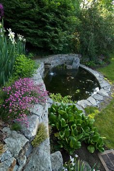 an outdoor pond surrounded by rocks and flowers