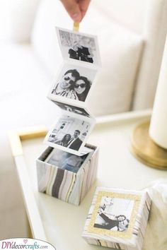 a stack of photos sitting on top of a table next to a candle and pictures