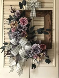 a wreath with flowers hanging on the front door