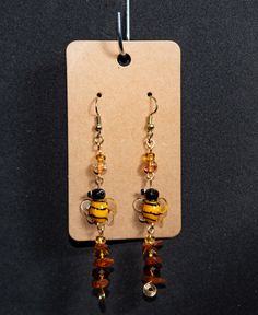 These bee-autiful drop earrings are sure to be the buzz around the hive! featuring cute glass bees with a honey drop made from glass beads.  . . All of the items in our shop are handmade with care. Unless otherwise specified, all of our beads are ceramic or glass and charms are cast metal. We consider small cosmetic flaws another facet of the beauty in our products, and often purchase or repurpose flawed or imperfect pieces for our work. However, none of these flaws should impact the durability of our jewelry. A note on purchasing earrings:  If you have a metal allergy please purchase with care as we do use a variety of wires and charms in our pieces. That being said, if you would like to request that we substitute nickel-free earring hooks please reach out to us in the cart notes and we'd Honey Drops, Buzzy Bee, Nickel Free Earrings, Bee Earrings, Metal Casting, Charms, Jewelry Earrings Dangle, Glass Beads, Bee