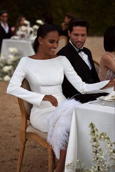 a man and woman sitting next to each other at a table with white cloths