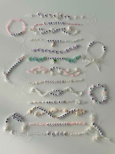 several bracelets are arranged in rows on a white surface, with beads attached to them