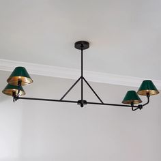 a chandelier with three green lamps hanging from it's sides in a room