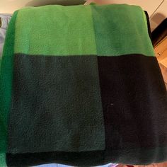 a green and black blanket sitting on top of a bed