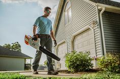 a man holding a chainsaw in front of a house