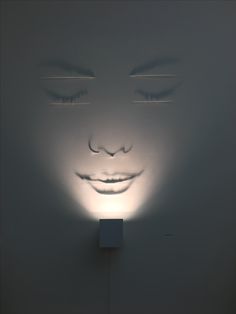 a light that is on the side of a wall with a face drawn on it