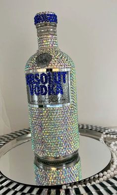 a bottle that is sitting on top of a glass table with some beads around it