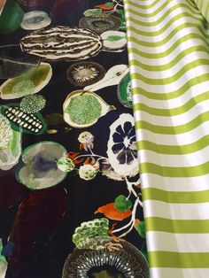 the fabric is green and white with many different designs on it's side, along with black and white stripes