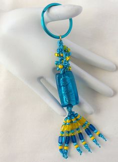 a blue and yellow beaded necklace hanging from a white mannequin's arm