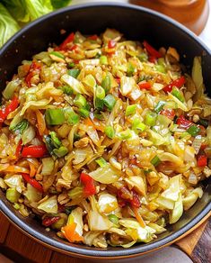 a skillet filled with stir fry vegetables on top of a wooden cutting board next to lettuce