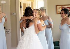 two brides hugging each other in front of the mirror while they are getting ready for their wedding