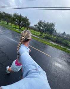 a woman is running in the rain with her arm wrapped around her waist and holding an umbrella over her head