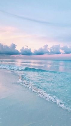 an ocean beach with waves crashing on the shore and clouds in the sky above it