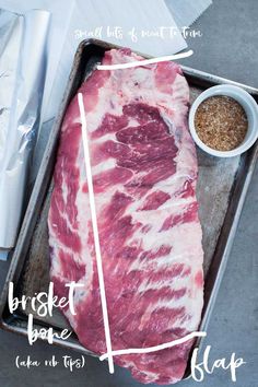 a piece of raw meat sitting on top of a pan next to some seasoning