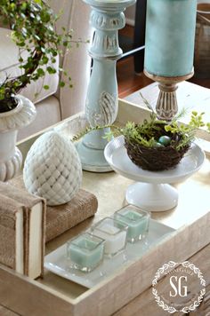 a table topped with two vases filled with plants and an egg sitting on top of a plate