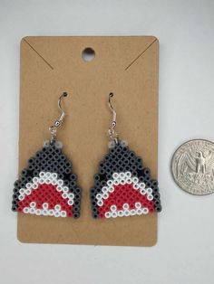 a pair of beaded earrings sitting next to a penny