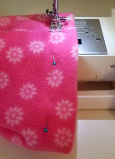 a pink blanket with white flowers is next to a sewing machine