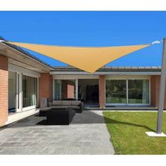 an outdoor area with a couch, table and large yellow shade sail on the roof