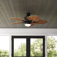 the ceiling fan is hanging from the ceiling in front of two large windows with black shutters