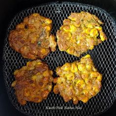 four hamburger patties cooking on the grill in an air fryer with corn kernels