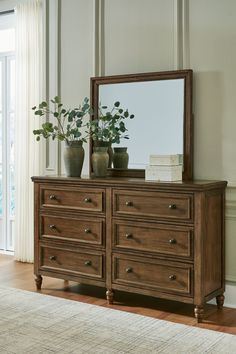 a wooden dresser with two vases and a mirror