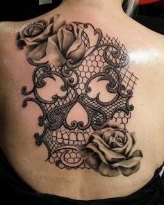 the back of a woman's shoulder with an intricate lace and rose tattoo design