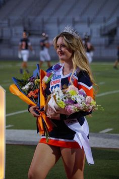 a beautiful young woman holding flowers on top of a field