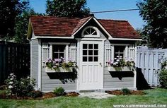 a garden shed with flowers in the window boxes