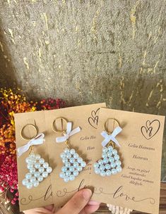 three pairs of earrings are shown in front of a card with the words love written on it