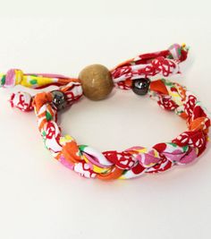 two bracelets with different colored cords and beads on white surface, one has a wooden bead in the middle